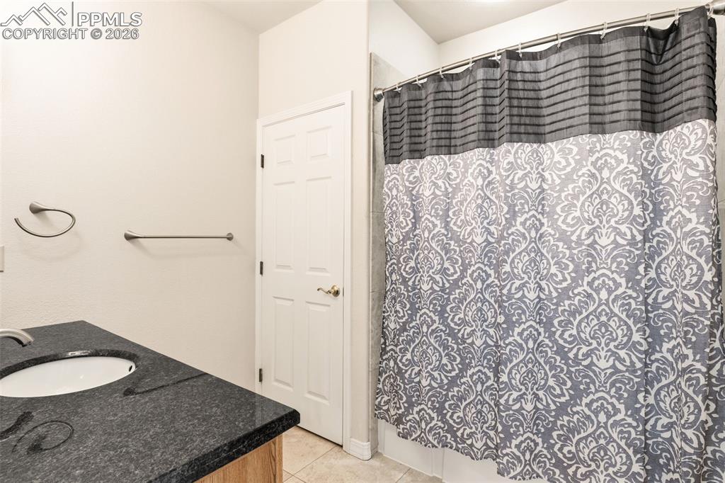 Image 21 of 43: Full bath featuring vanity, curtained shower, and light tile patterned floo