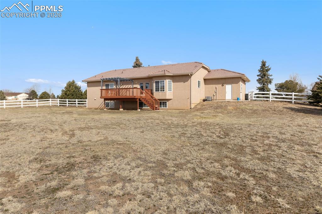 Image 42 of 43: Back of house featuring a fenced backyard, a deck, and stucco siding