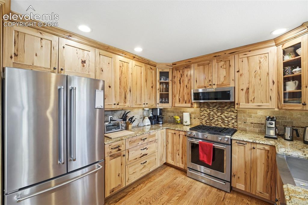 Image 13 of 41: Kitchen featuring natural wood cabinetry, stainless steel appliances, grani