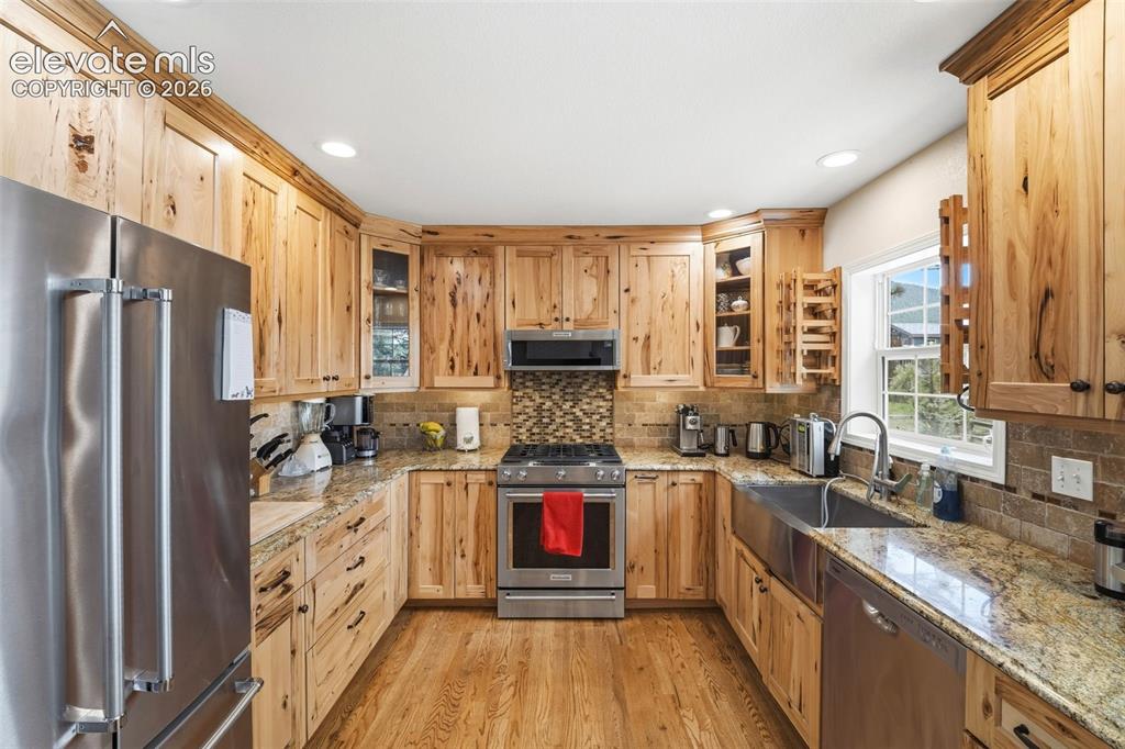 Image 14 of 41: Kitchen featuring natural wood cabinetry, stainless steel appliances, grani