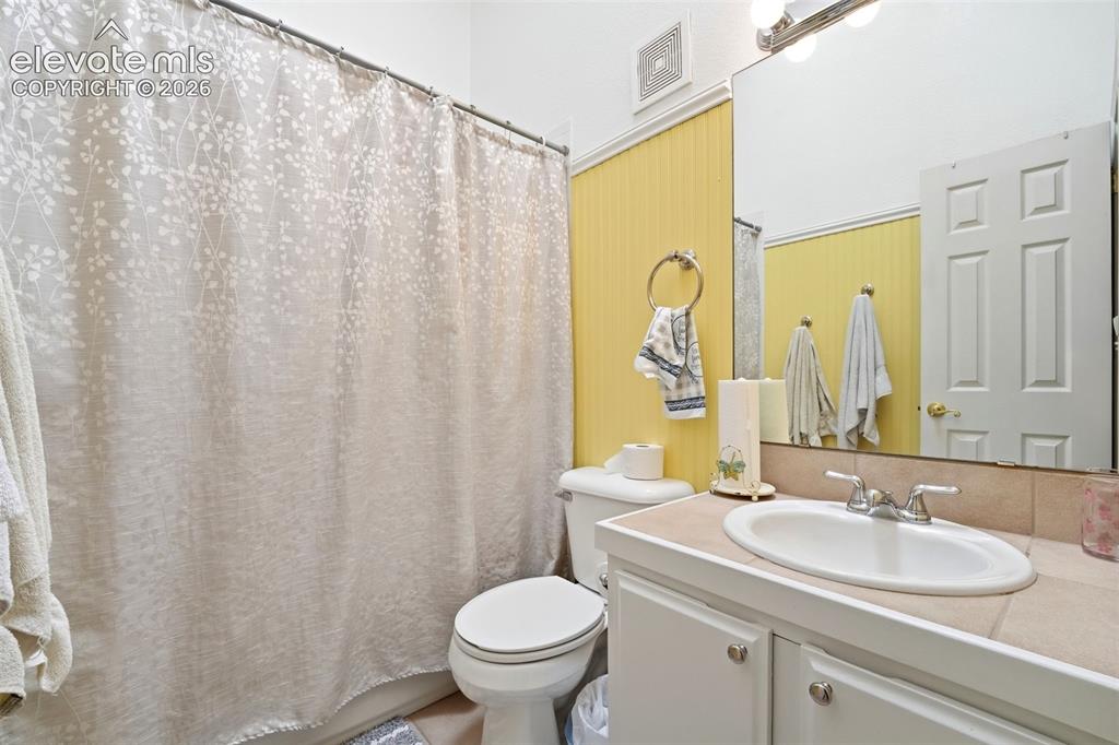 Image 23 of 41: Bathroom with a single vanity, a large mirror, and a shower with a curtain