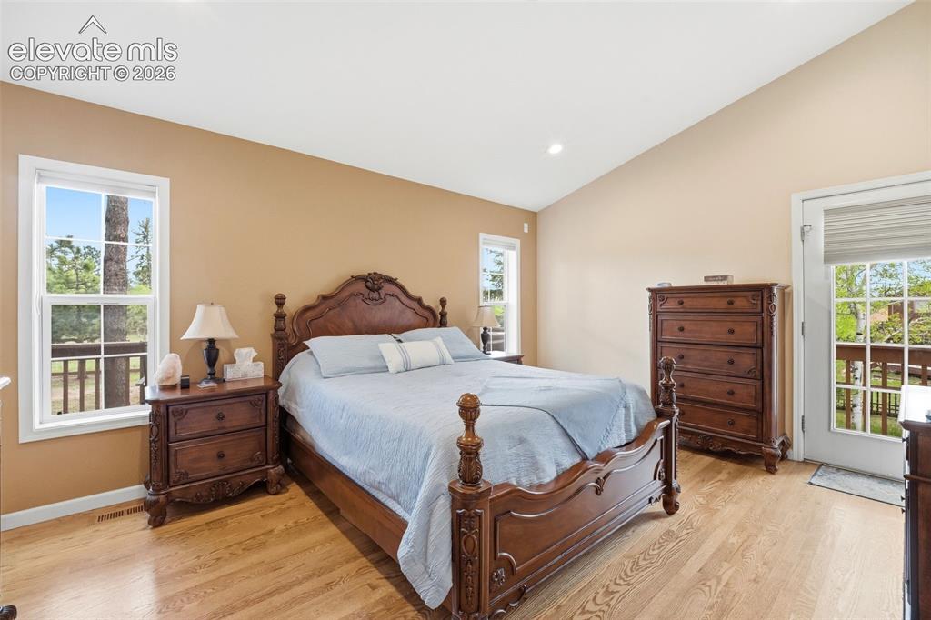 Image 26 of 41: Vaulted ceiling bedroom featuring wood-finish flooring and two double-pane