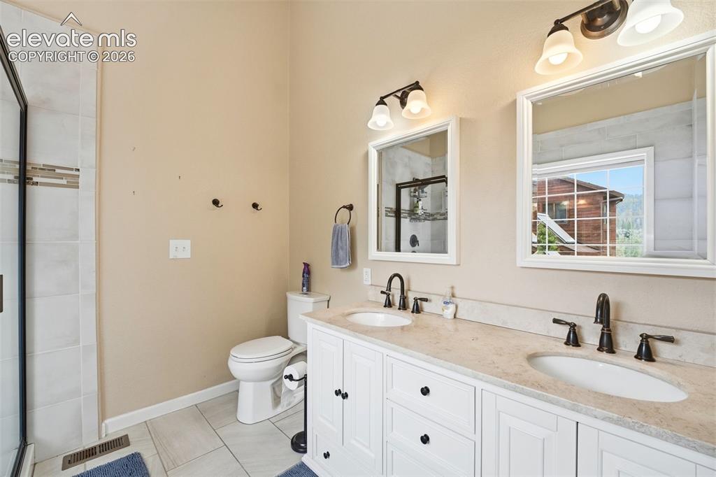 Image 28 of 41: Bathroom featuring a double vanity with white cabinetry, light-toned counte