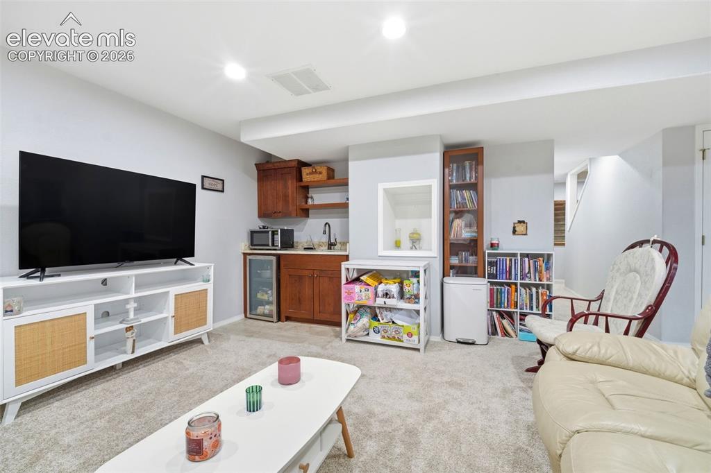 Image 29 of 41: Carpeted lower level featuring a built-in wet bar with wood cabinetry and a