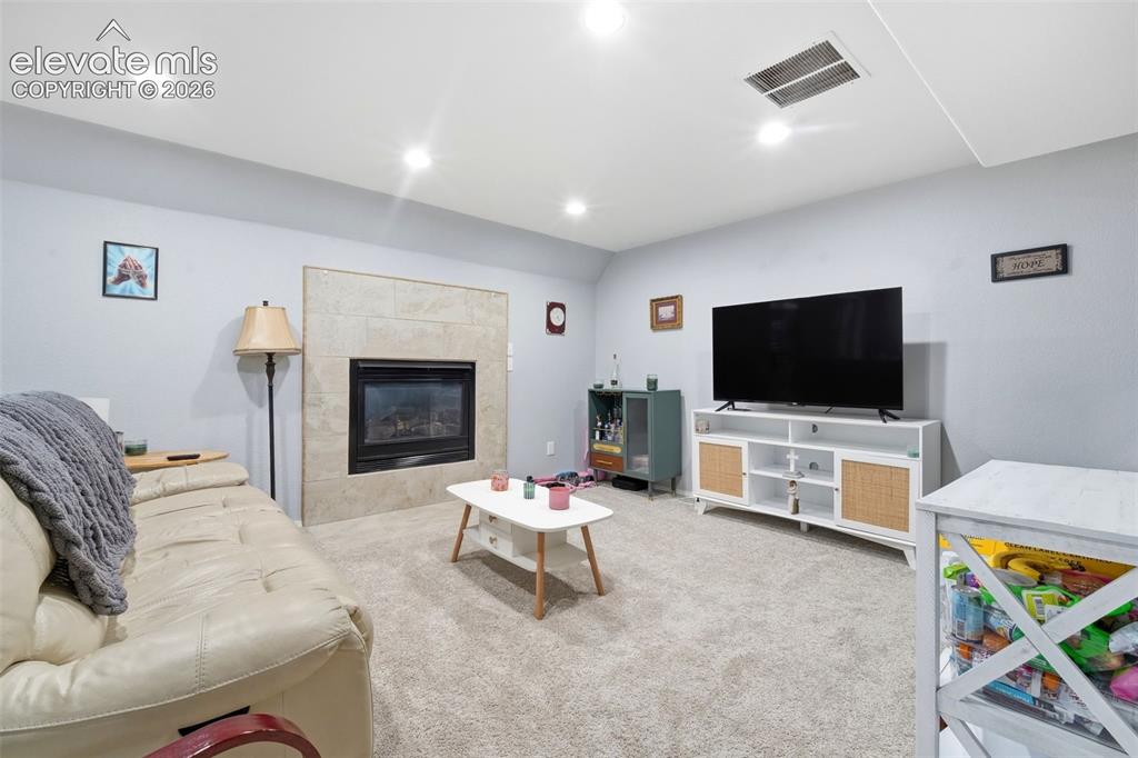 Image 31 of 41: Recessed lighting illuminates a carpeted living space featuring a tile-surr