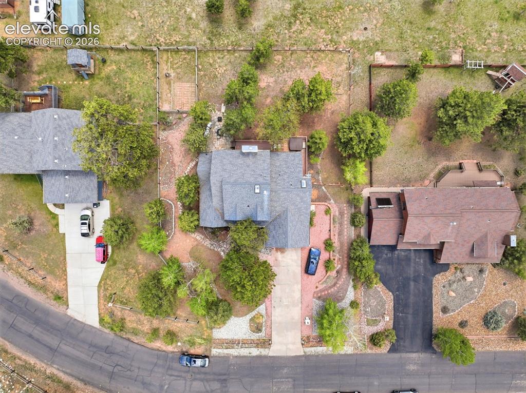 Image 35 of 41: Central property featuring a gray shingle roof, paved driveway, and mature