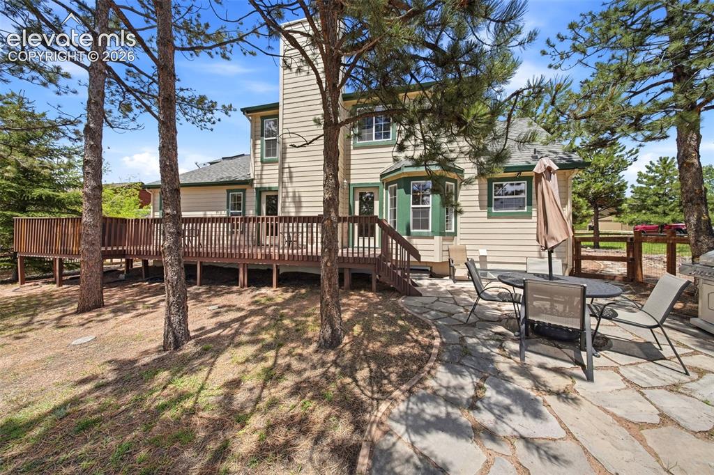 Image 36 of 41: Expansive wood deck with full railing, complemented by a stone patio featur