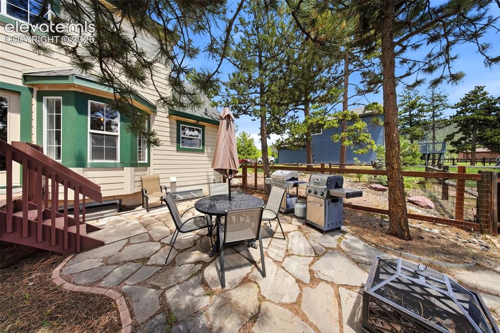 Image 38 of 41: Flagstone patio featuring a bay window, wood-finish siding, and mature tree