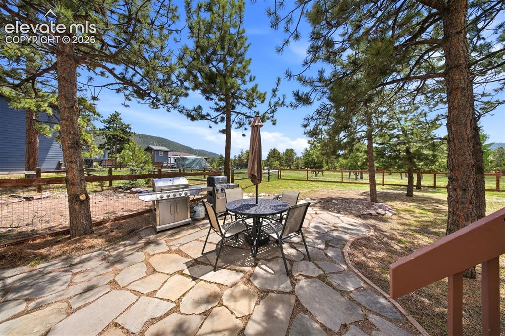 Image 39 of 41: Flagstone patio with an expansive fenced yard and mature pine trees