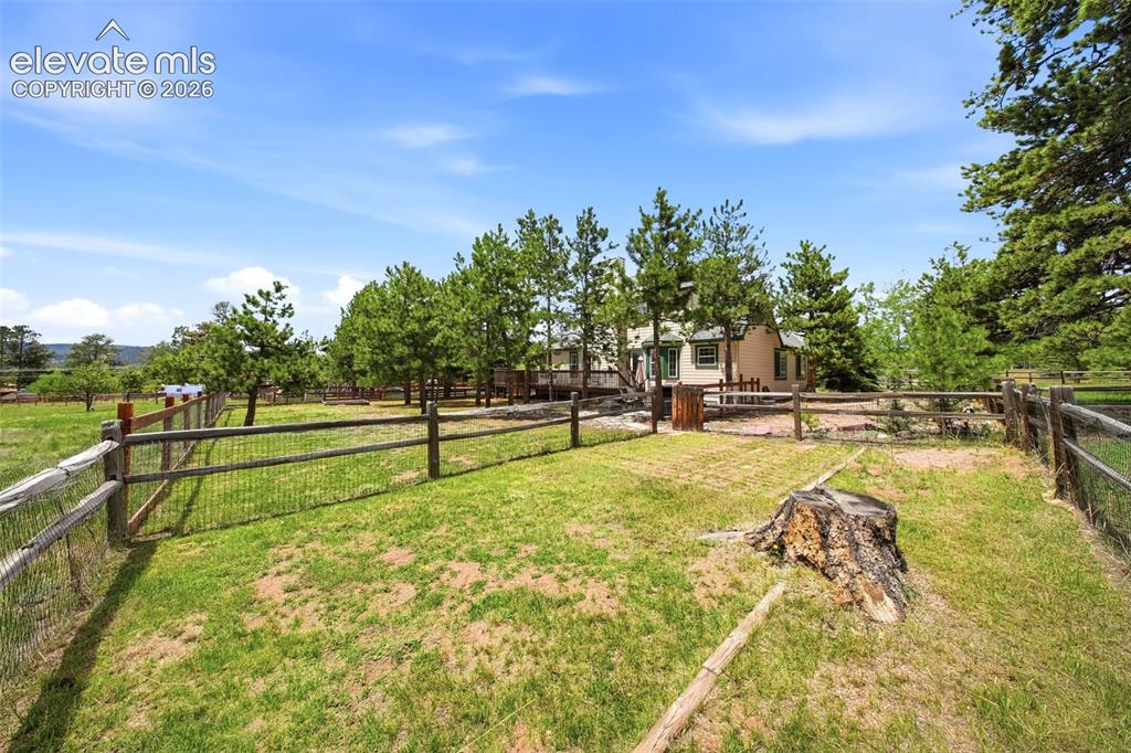 Image 4 of 41: Expansive grounds featuring a wood rail fence with wire mesh, mature trees,