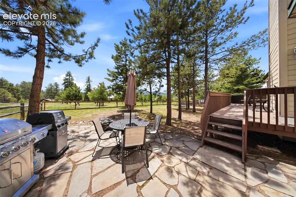 Image 40 of 41: Stone patio with a slatted privacy fence