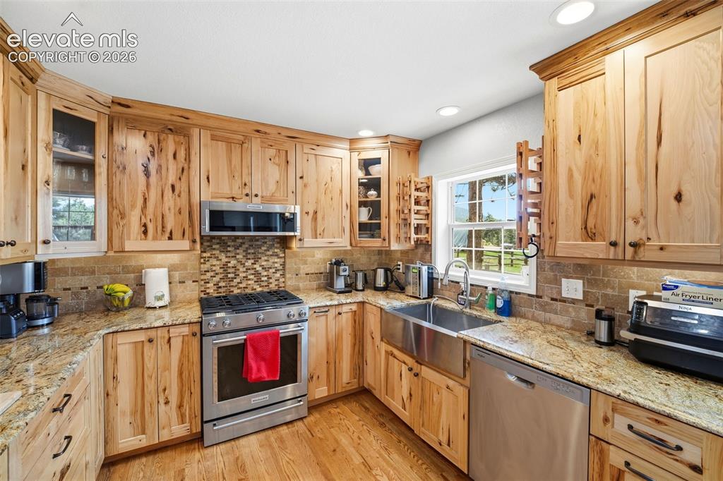 Image 5 of 41: Kitchen featuring natural wood cabinetry, light-toned granite countertops,
