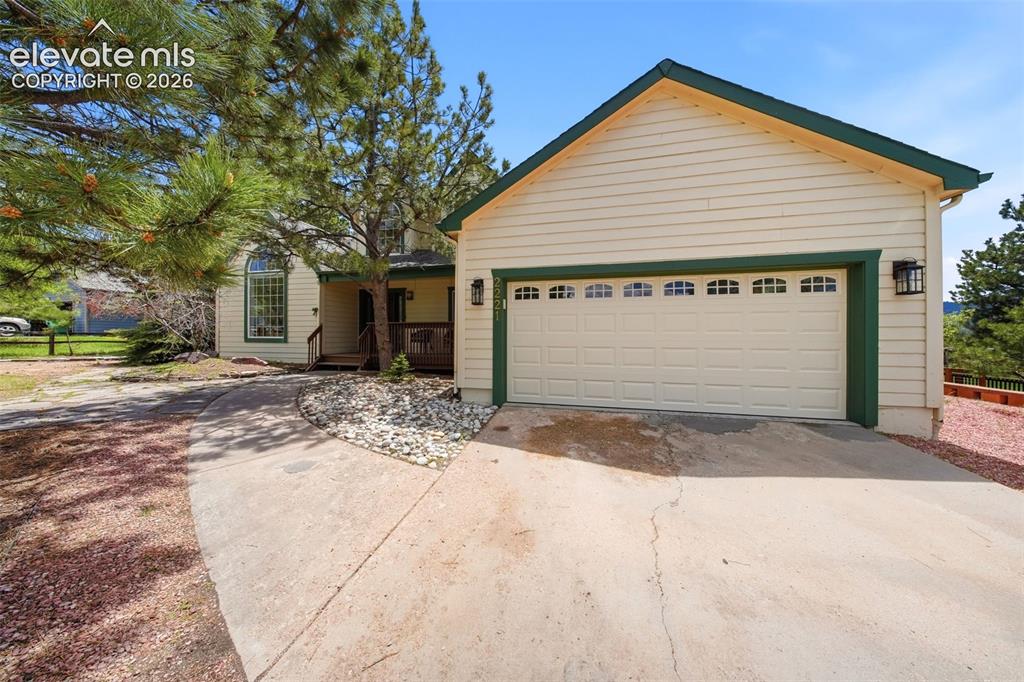 Image 6 of 41: Light-colored siding exterior with dark green trim and a two-car garage