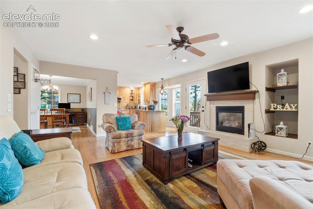 Image 8 of 41: Living area featuring a gas fireplace with a stone surround, a wood mantel,