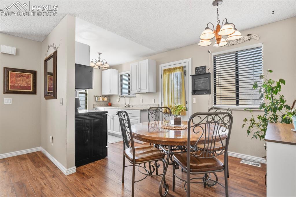 Image 10 of 32: Dining room with suspended lighting, a textured ceiling, and dark wood-type