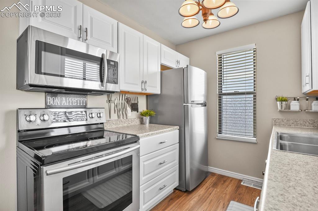 Image 11 of 32: Kitchen with stainless steel appliances, light countertops, white cabinetry