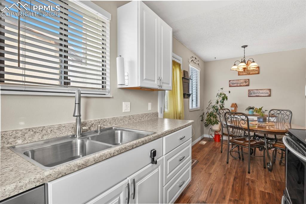 Image 13 of 32: Kitchen with white cabinets, light countertops, dark wood-type flooring, ha