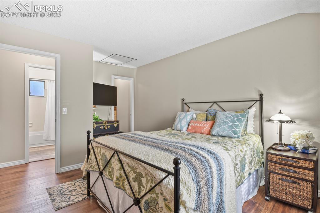 Image 15 of 32: Bedroom with dark wood finished floors and baseboards