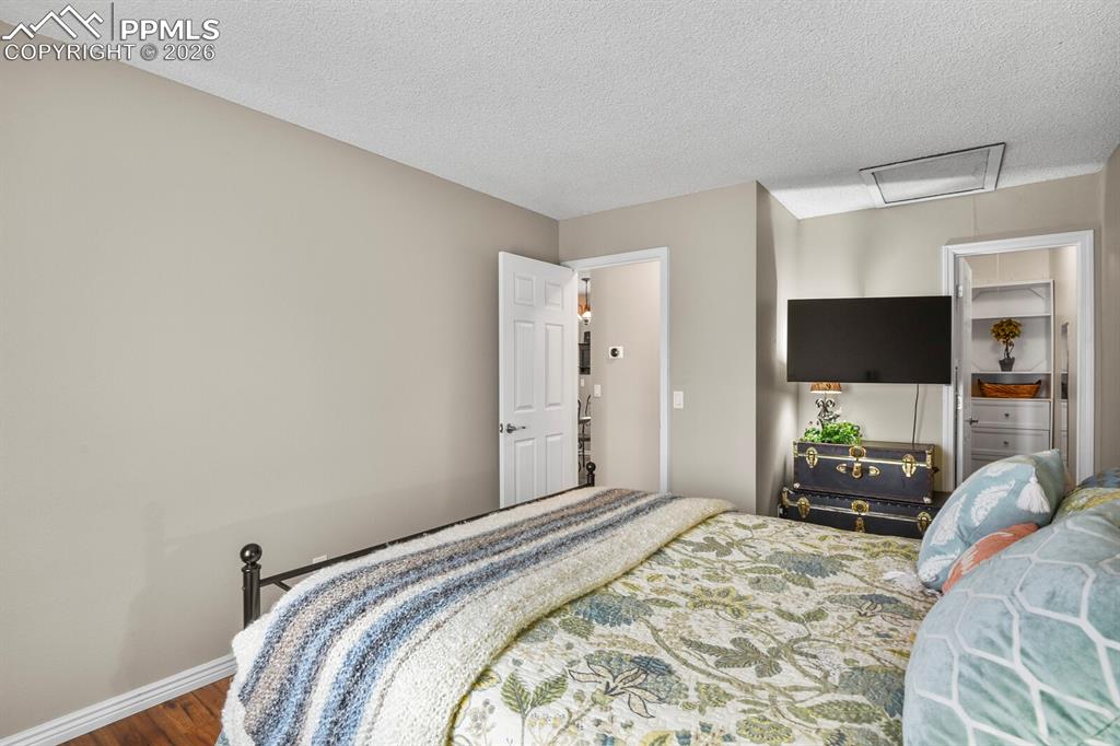 Image 16 of 32: Bedroom with dark wood finished floors and a textured ceiling