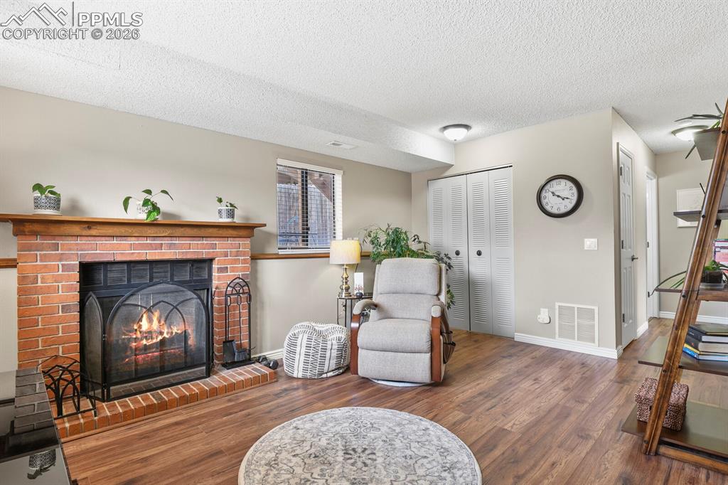 Image 19 of 32: Sitting room featuring wood finished floors, a textured ceiling, and a fire