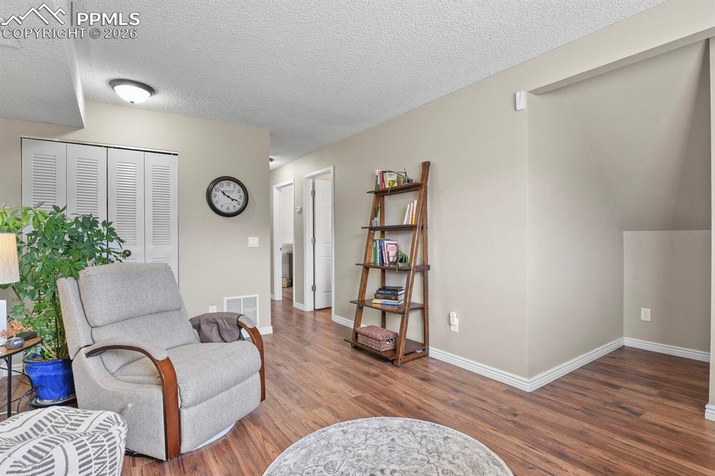 Image 21 of 32: Living area with dark wood-type flooring and a textured ceiling