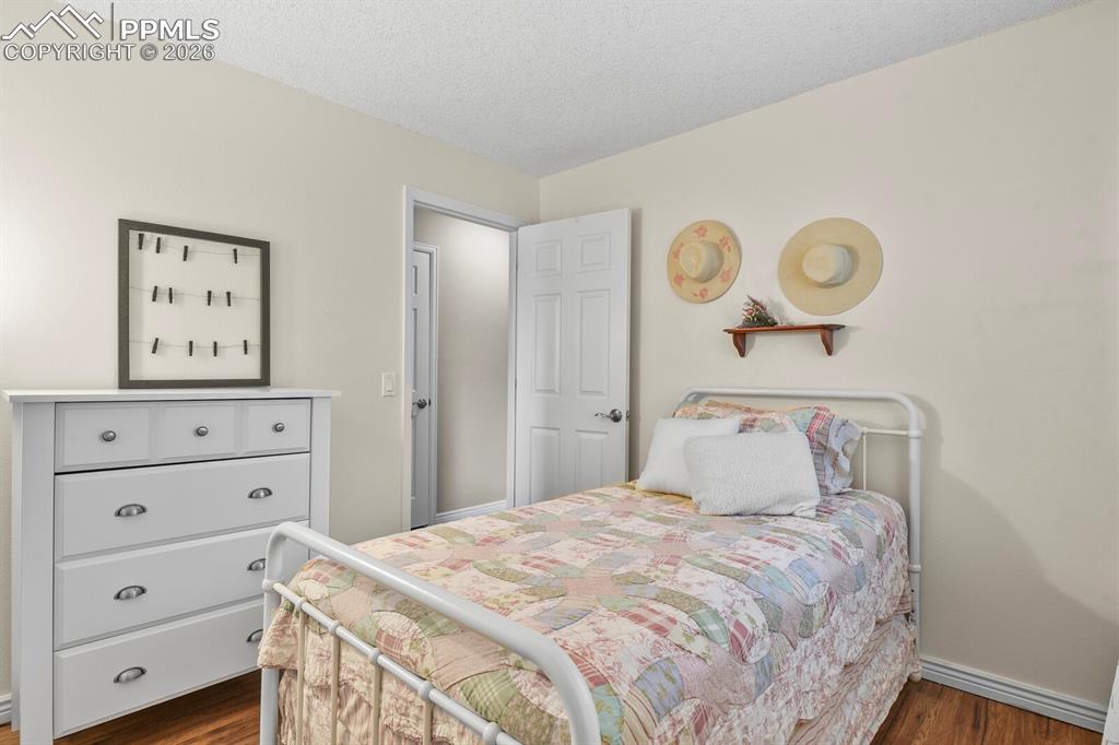 Image 23 of 32: Bedroom with a textured ceiling and dark wood finished floors