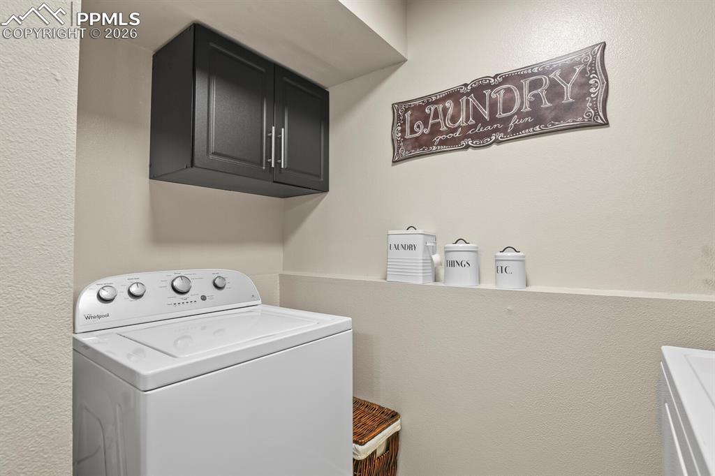 Image 28 of 32: Laundry room featuring washer / clothes dryer, a textured wall, and cabinet