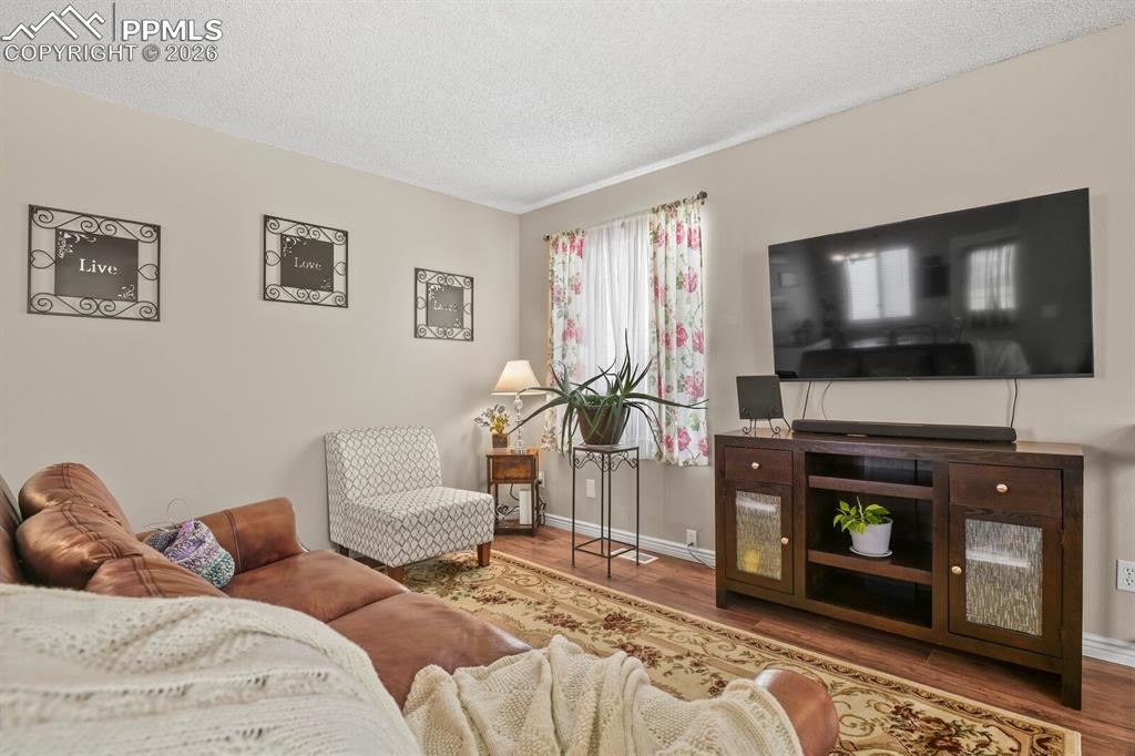 Image 4 of 32: Living area with a textured ceiling and wood finished floors