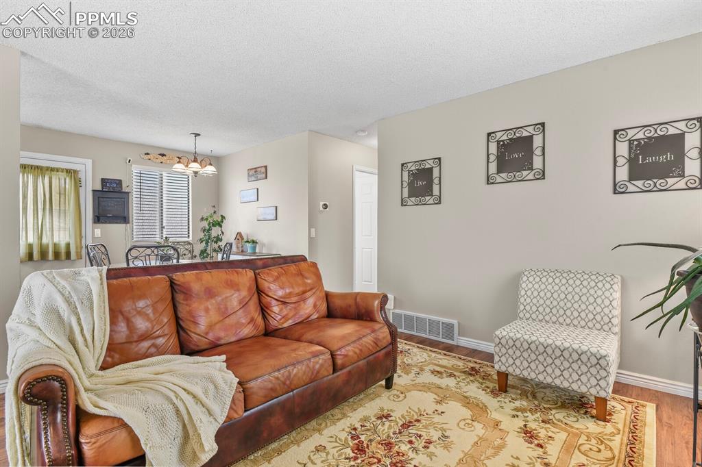 Image 5 of 32: Living area with a chandelier and wood finished floors