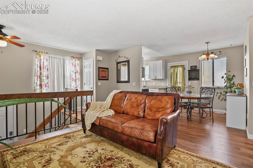 Image 6 of 32: Living area featuring wood finished floors, a textured ceiling, a ceiling f