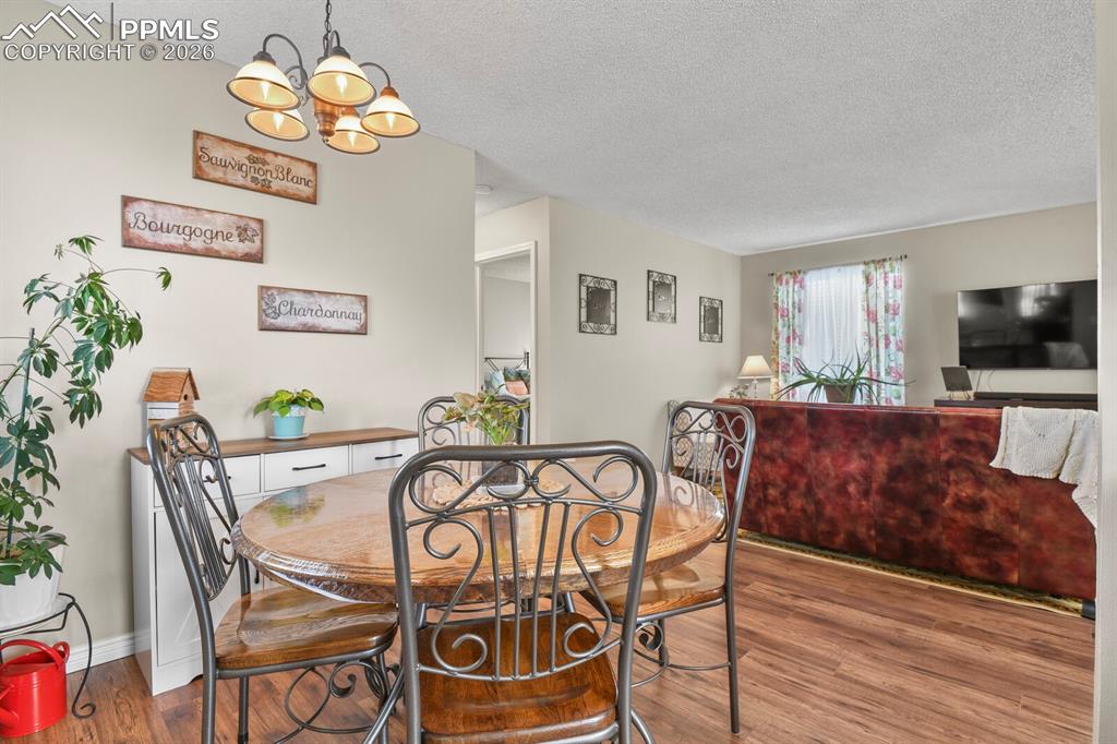Image 8 of 32: Dining area with hanging lights, a textured ceiling, and dark wood-type flo