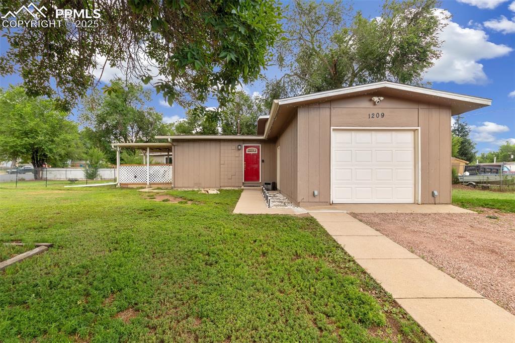 Caption: View of front of house with dirt driveway and an attached garage