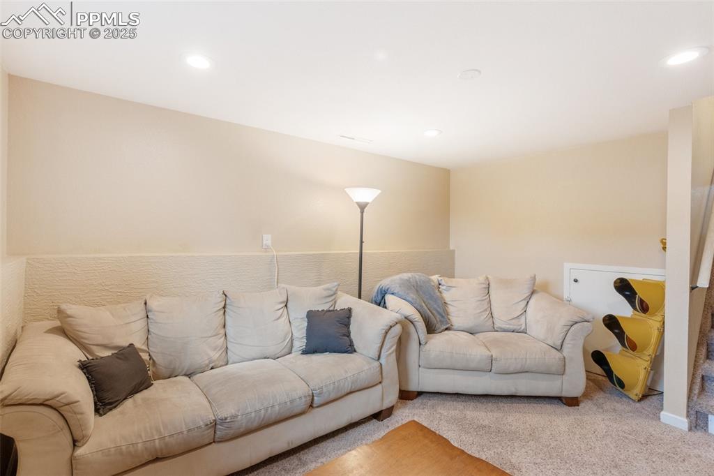 Image 11 of 35: Living area with light colored carpet and recessed lighting