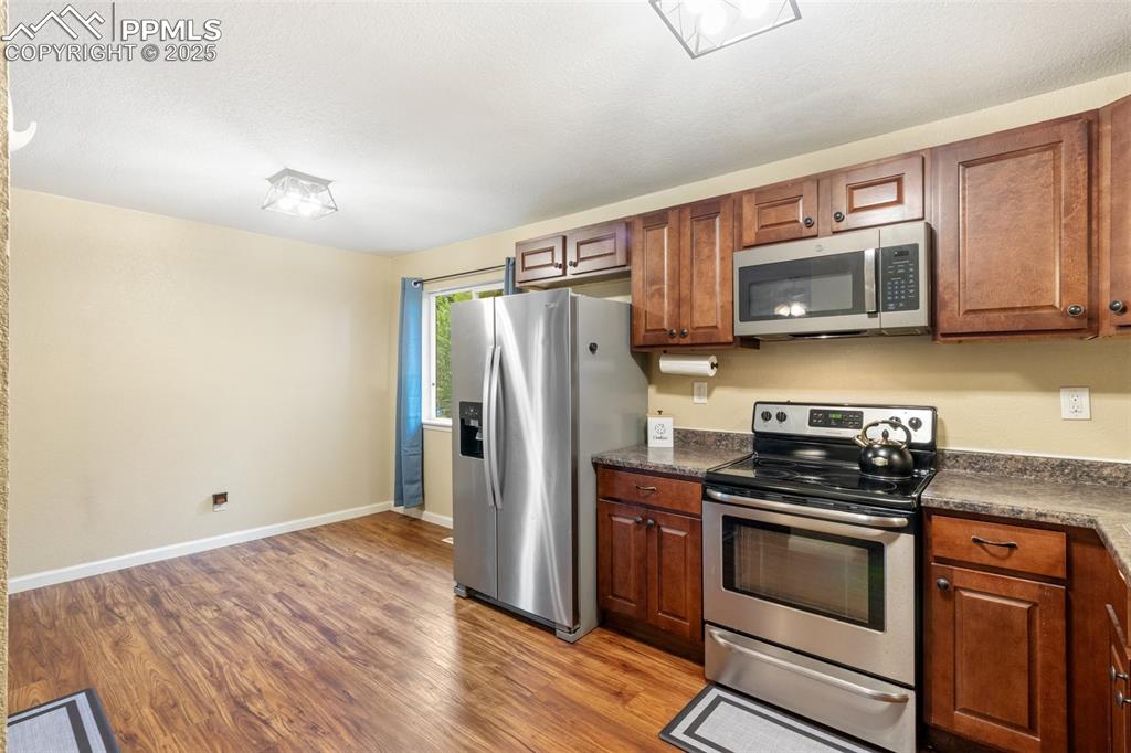 Image 12 of 35: Kitchen with appliances with stainless steel finishes, dark countertops, li