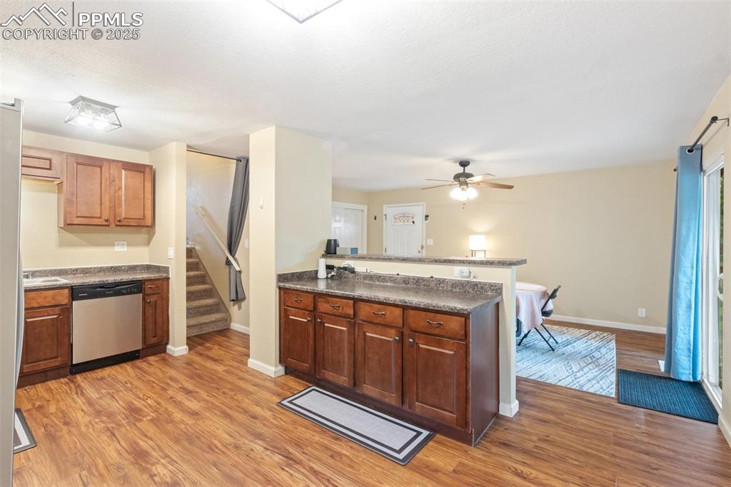 Image 13 of 35: Kitchen with dishwasher, a peninsula, light wood finished floors, dark coun