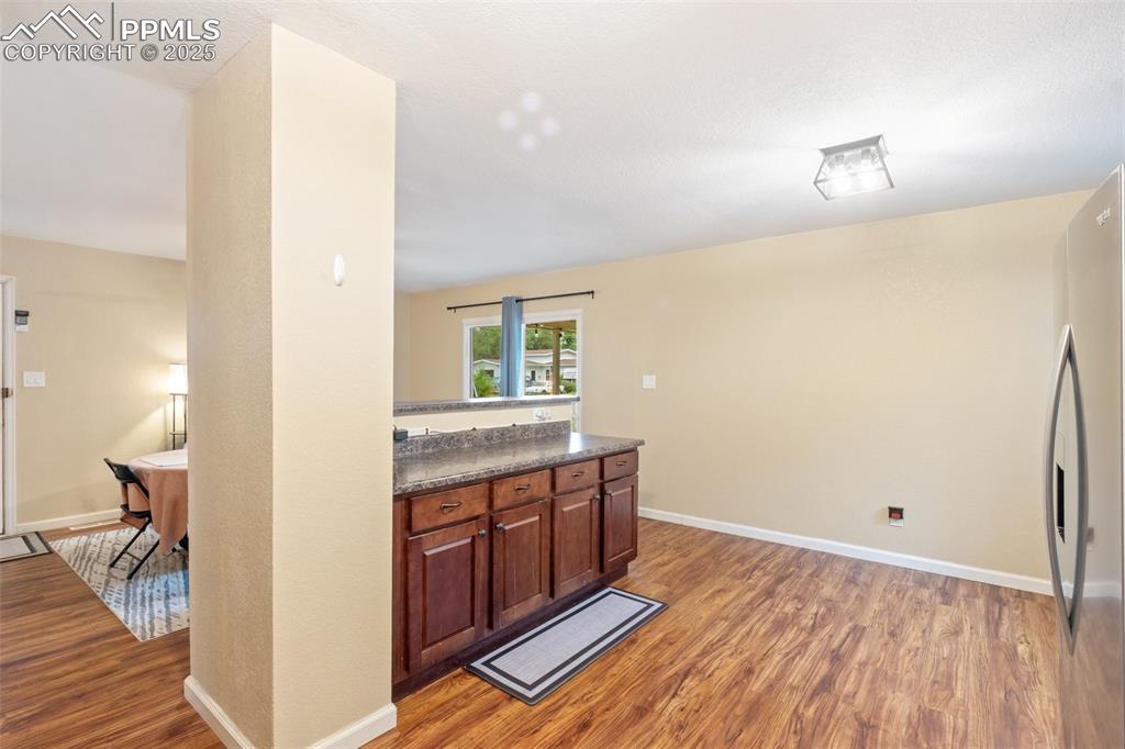 Image 15 of 35: Kitchen featuring light wood-style flooring, dark countertops, and freestan