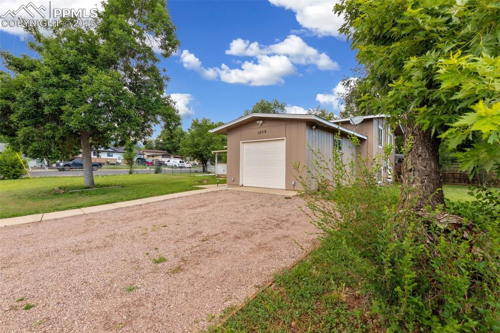 Image 2 of 35: Garage with dirt driveway
