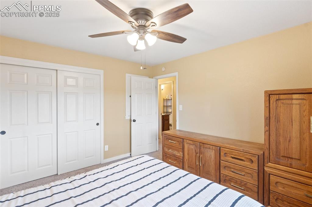 Image 25 of 35: Bedroom with a closet, light carpet, and ceiling fan