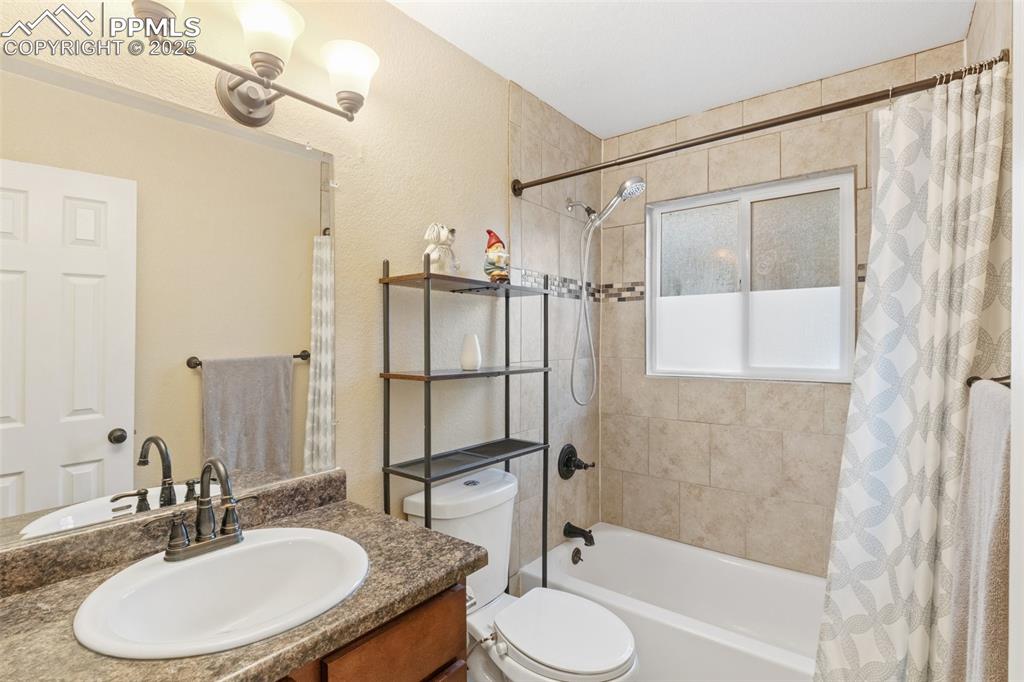 Image 27 of 35: Bathroom featuring shower / bath combo, vanity, and a textured wall