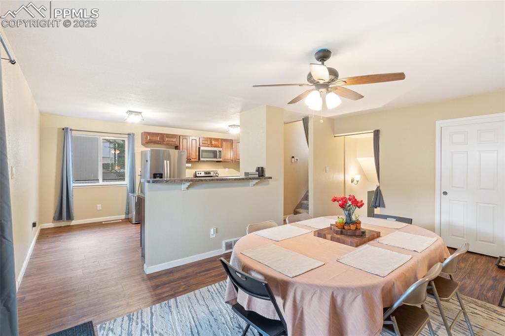 Image 8 of 35: Dining room with stairway, dark wood-style flooring, and a ceiling fan