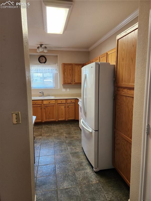 Image 19 of 19: Kitchen featuring fridge, dark stone finish floors, light countertops, orna