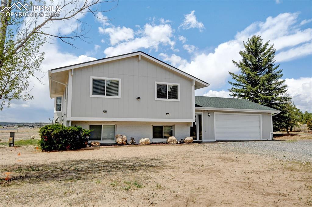 Image 2 of 40: Rear view of house with brick siding, a garage, and driveway