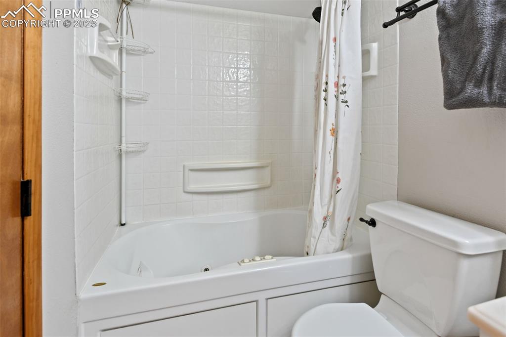 Image 21 of 40: Full bath with a combined bath / shower with jetted tub and toilet