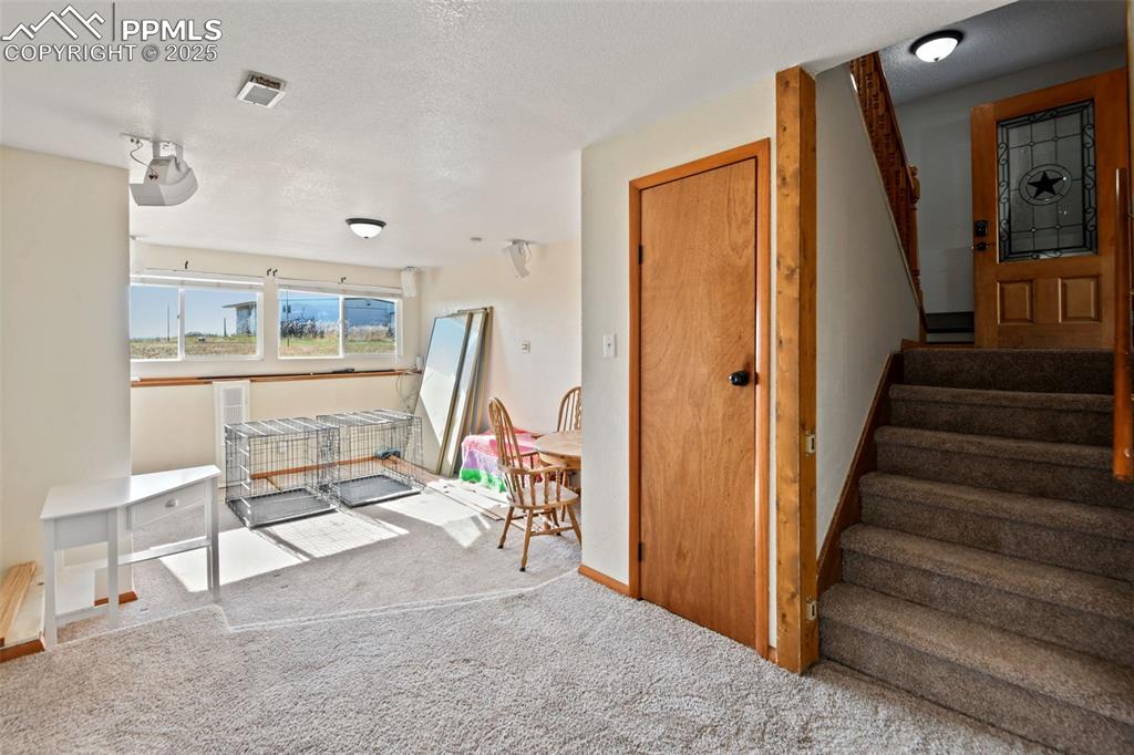 Image 27 of 40: Stairway featuring a textured ceiling and carpet flooring