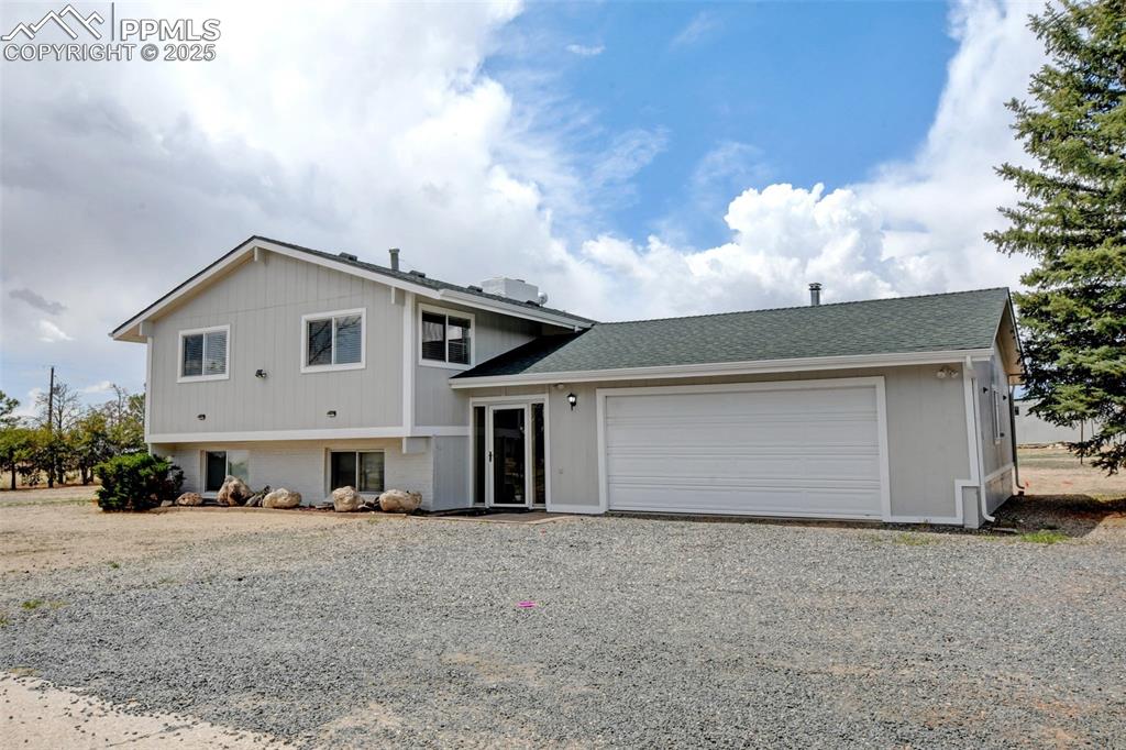 Image 3 of 40: Tri-level home with driveway, a garage, and roof with shingles