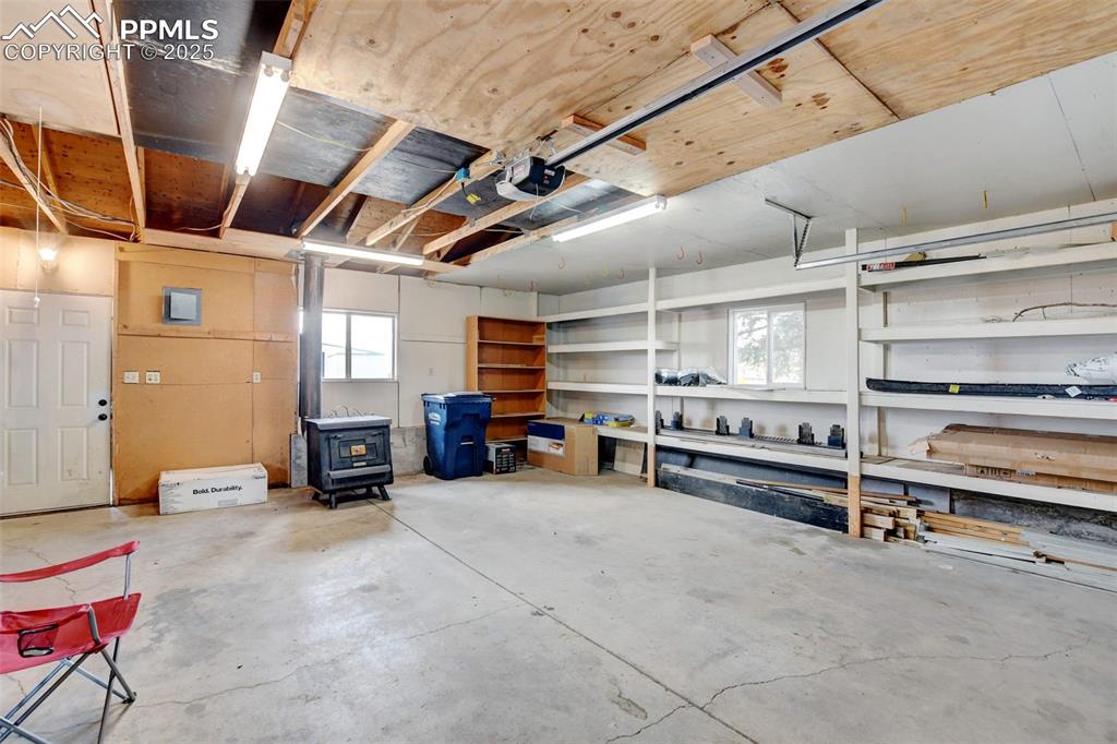 Image 31 of 40: Garage with a wood stove and a garage door opener