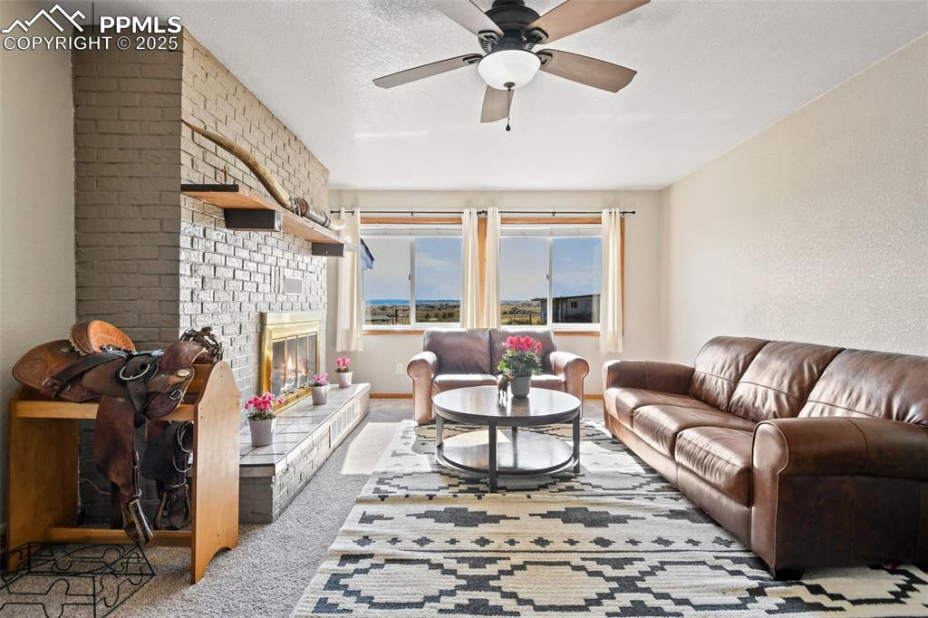 Image 6 of 40: Carpeted living room with a brick fireplace and a ceiling fan