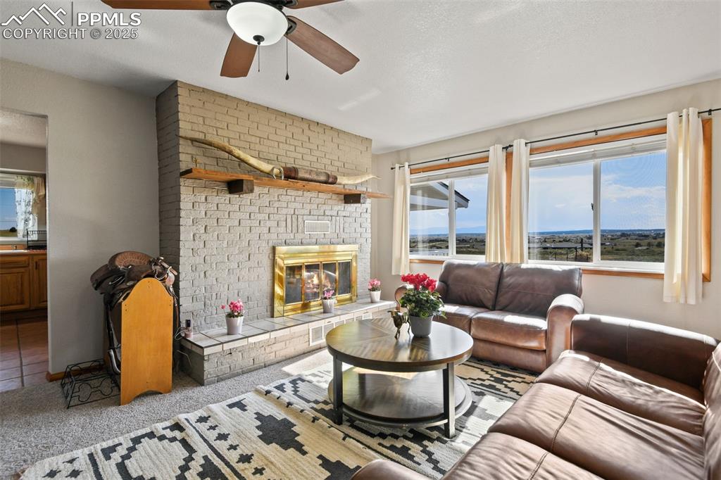 Image 8 of 40: Living room featuring carpet, a brick fireplace, and a ceiling fan