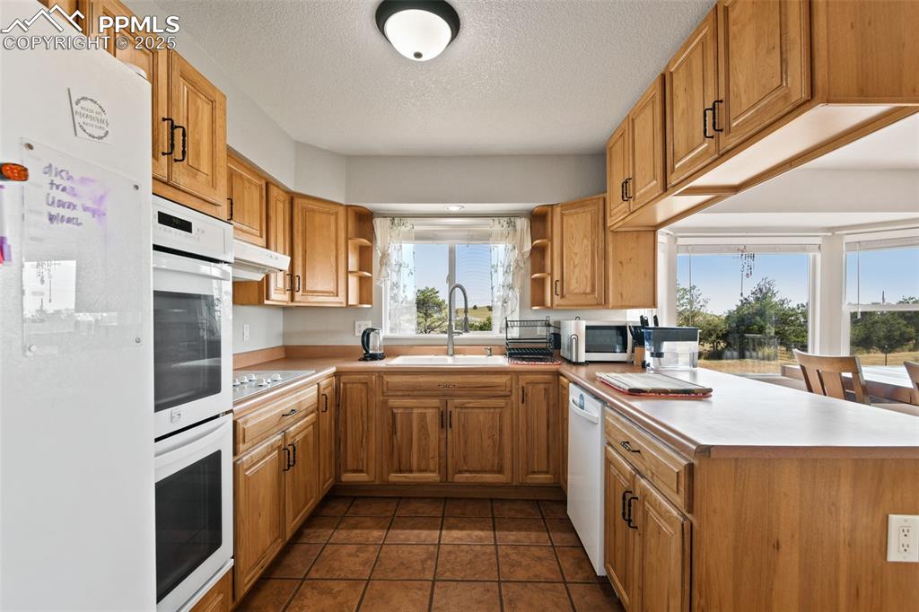 Image 9 of 40: Kitchen featuring white appliances, open shelves, light countertops, a text