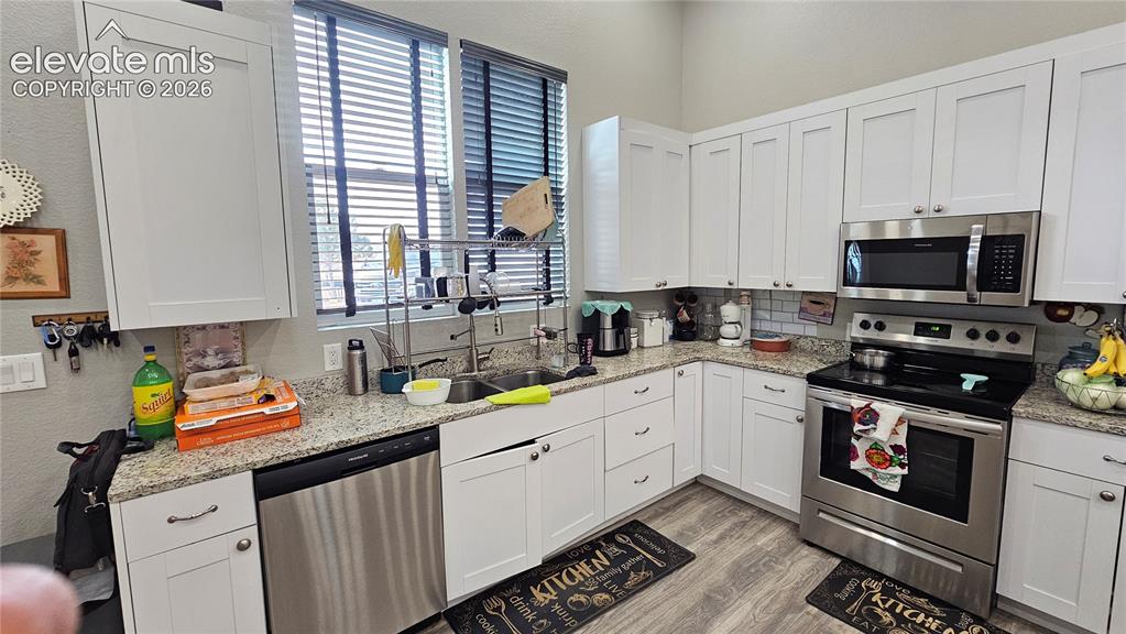 Image 14 of 48: Kitchen featuring white shaker cabinetry, stainless steel appliances, speck